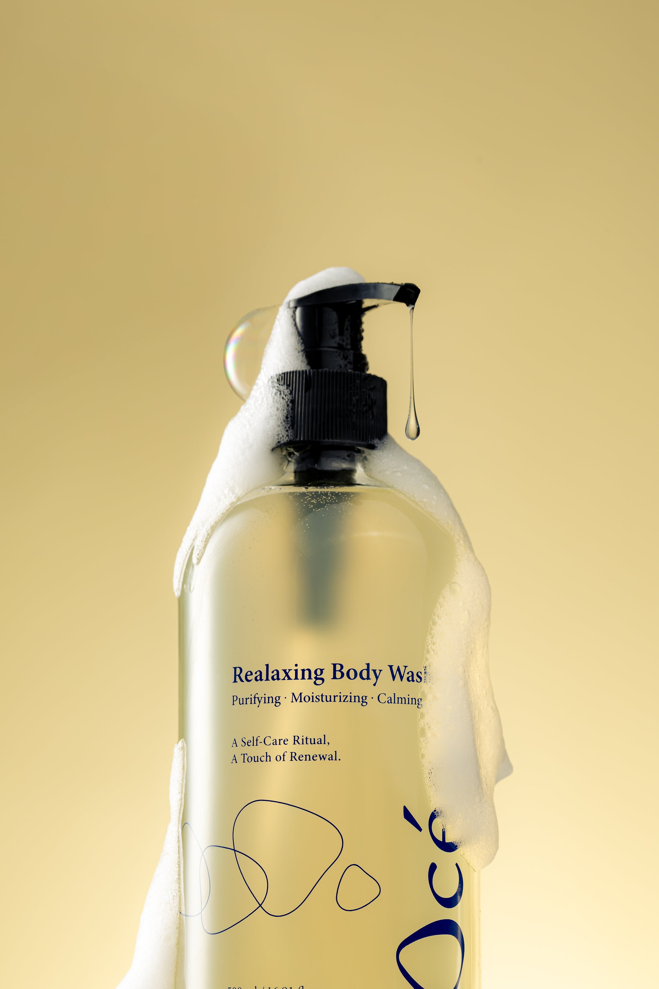 Bottle of Ocea Realaxing Body Wash in foam with a pump on a yellow background